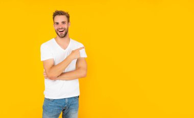 Beyaz gömlekli neşeli, traşsız genç adam sarı arka planda işaret parmağı, yaşam tarzı