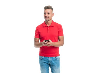 Kırmızı tişörtlü gülümseyen adam beyaz arka planda izole akıllı telefondan mesaj yolluyor.