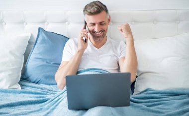 Olgun bir adamın telefonda konuşmasına ve laptopla yatakta çalışmasına sevindim.