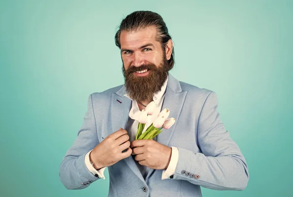 well groomed man in wedding formalwear has beard hold tulip flower, date