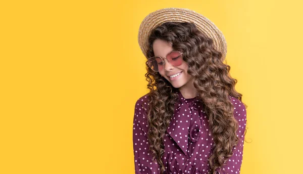 Gaie fille en paille chapeau et lunettes de soleil avec de longs cheveux bouclés brune sur fond jaune — Photo