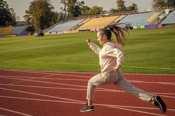Zasada biegania to po prostu ucieczka. Energiczna dziewczyna biegnie po torze. Szkoła sportowa — Zdjęcie stockowe