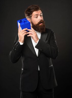 Siyah arka planda smokinli, papyon takan, erkek erkeğe giyinen meraklı bir adam.