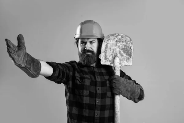 Homem construtor brutal em uniforme e capacete com pá, dia de trabalho — Fotografia de Stock