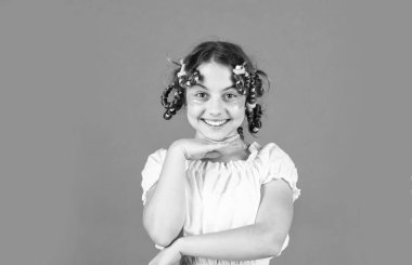 Moda ipuçları. Gençlik hobileri. Kıvırcık saçlı, turuncu saçlı küçük bir kız. Kafasında bigudileri olan kızı gülüyor. Kuaför salonu. Sevimli çocuk saçı. Kadın güzellik rutini