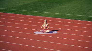 Spor salonundaki atletik kadın stadyumda yoga yapıyor.