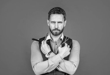 Sakallı adam, kırmızı arka planı kesmek ve traş etmek için eski berber aletlerini tut, berber.