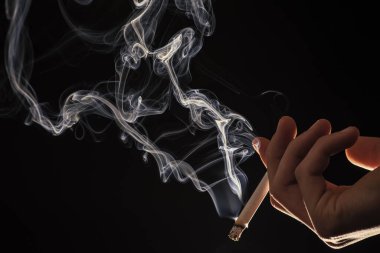 Tütün manyaktır. Erkek elinde dumanı tüten sigara. Sigara içme alışkanlığı. Tütün dumanı