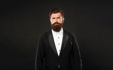 serious man in tuxedo bow tie looking forward. gentleman in formalwear on black background.