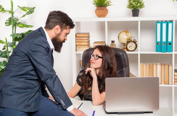 Flirty office manager flirting with director sitting on office desk, work relation