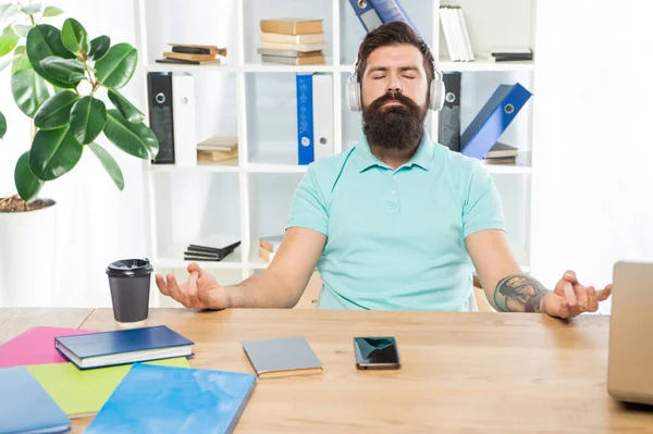 Rauhallinen mies meditoida pitää mudra kuunnella rentouttavaa musiikkia kuulokkeet toimistopöytä, meditaatio — kuvapankkivalokuva
