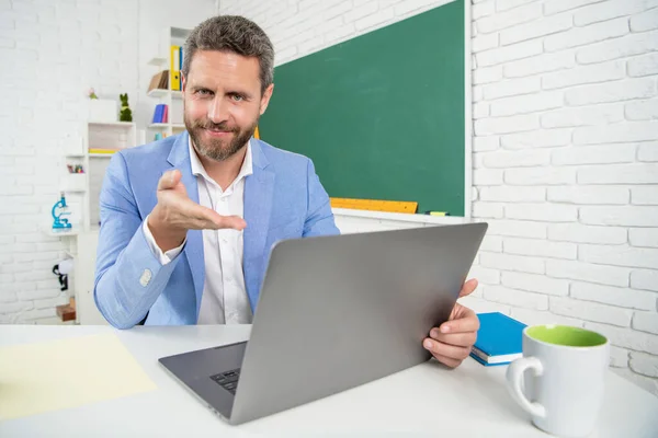 Happy school teacher in classroom with computer at blackboard — Stock Fotó