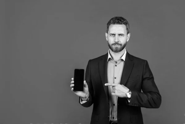 Hombre guapo en ropa formal que presenta el producto de teléfono inteligente, espacio de copia, publicidad — Foto de Stock