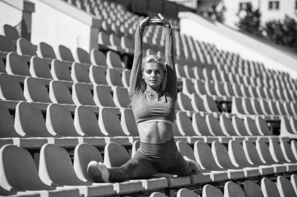 Sexy fitness kobieta rozciągające się w odzież sportowa siedzieć w split na stadionie, split — Zdjęcie stockowe