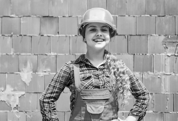 건축 현장에서 헬멧을 쓰고 있는아이. 군복을 지은 십 대 소녀. 아이가 수리를 하고 있습니다. 워크숍의 보수 개념. 분주 한 직공 목수 — 스톡 사진