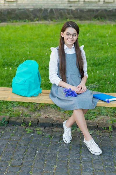 Happy child in glasses relax on school bench with flowers and backpack. womens day — Stok fotoğraf