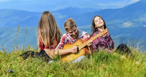 Melody of nature. Hiking tradition. Friends hiking with music. Nothing but friends and guitar. People relaxing on mountain top while handsome man playing guitar. Hiking entertainment. Peaceful place — Stockfoto