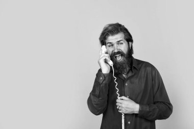 Tişörtlü, sakallı, vahşi, beyaz tenli hippi retro telefonda konuşuyor.