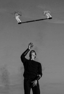 Açık havada mavi gökyüzünde yanan bastonla manipüle edilen erkek ateş sanatçısı.