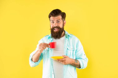 Elinde çay tabağı sarısı arka planda kahve içen mutlu adam, kır.