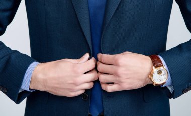Lüks kol saati olan resmi takım elbiseli bir adam.