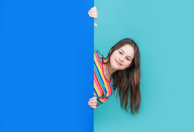 Boş mavi kağıdın arkasında reklam için fotokopi alanı olan mutlu bir çocuk.