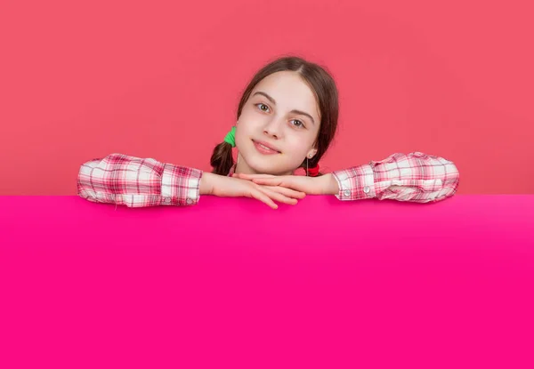 Barn leende bakom tomt rosa papper med kopia utrymme för reklam — Stockfoto