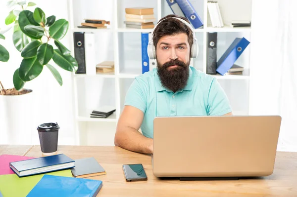 Serious man listening to webinar in headphones using laptop in office, online education — Foto de Stock