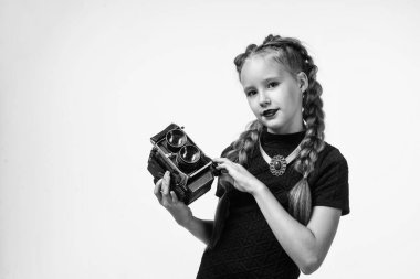 Genç kız fotoğraf çekiyor. Retro kamera. Mutlu çocukluk. Çocuğun şık bir görünüşü var. Modern hayatta fotoğrafçılık. Eski moda fotoğraf makinesi olan çocuk beyaza izole edilmiş. Eski teknoloji. Boşluğu kopyala