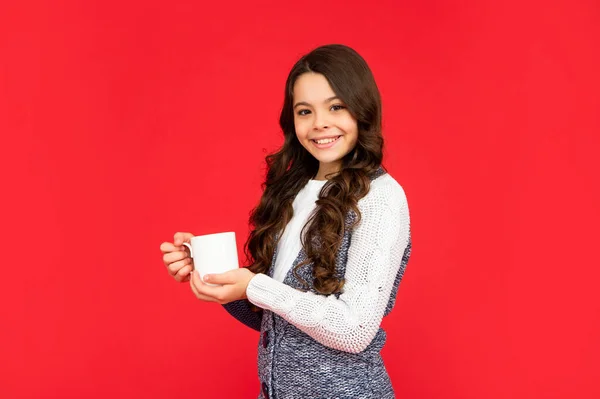 Positive teen girl drink warm tea on red background. portrait of child with coffee cup. — Stockfoto