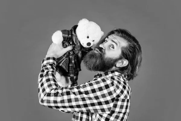 Brutal barbudo hombre desgaste a cuadros camisa tener exuberante barba y bigote beso peluche oso juguete, amor —  Fotos de Stock