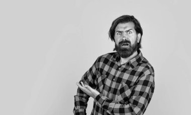 Şuraya bak. Sarı arka plandaki duygusal adam. Vahşi sakallı hippi. Bıyıklı, olgun bir adam. İnsan duygularını ifade etmek. Ürün sunumu. Kareli gömlekli, şaşkın bir adam.