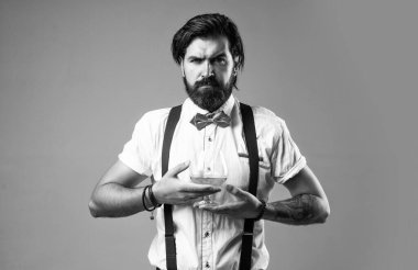 Papyonlu retro adam alkolle rahatlıyor. Klasik müziğin kendine güvenen barmeni brendi içer. Erkeklik ve karizma. Viski ve viski. Eski moda sakallı barmen.