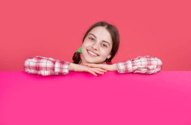 glad child behind blank pink paper with copy space for advertisement