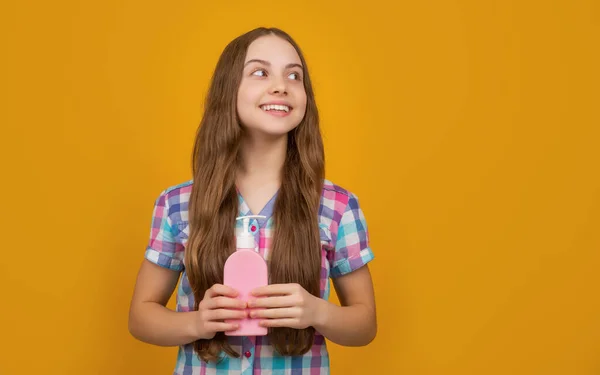 Happy kid with liquid soap bottle on yellow background — Stockfoto