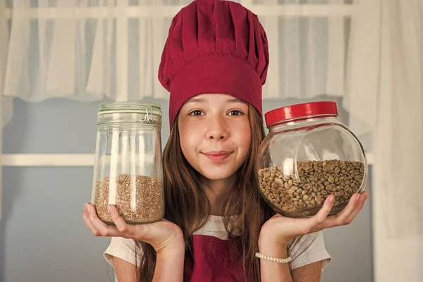 smiling child chef hold jar with coffee and grains, food