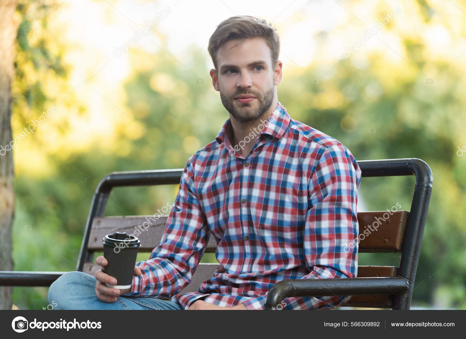 Young guy in checkered Stock with on bench by Photo park coffee cup shirt 566309892 ©stetsik