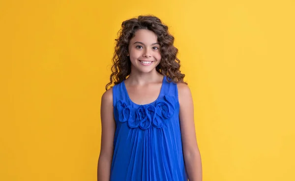 Cheerful child with long brunette afro hair on yellow background — Stock fotografie