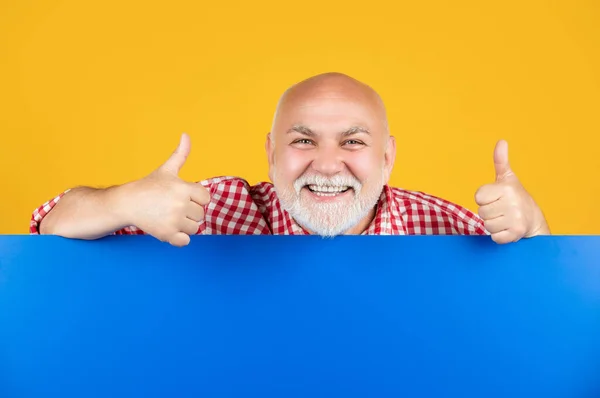 Felice uomo anziano con spazio per la copia su banner vuoto. presentazione del prodotto. pollice in su — Foto Stock