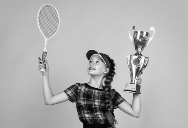 Győztes gyermek ütővel és bajnoki kupával. A tini lány megnyeri a tenisz bajnokságot. sport. teniszező vagy tollaslabda játékos. egészséges és aktív életmód. Tele energiával. Boldog gyermekkort. gyerek hold ütő — Stock Fotó