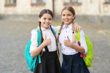 happy kids friends together in school uniform with backpack. thumb up