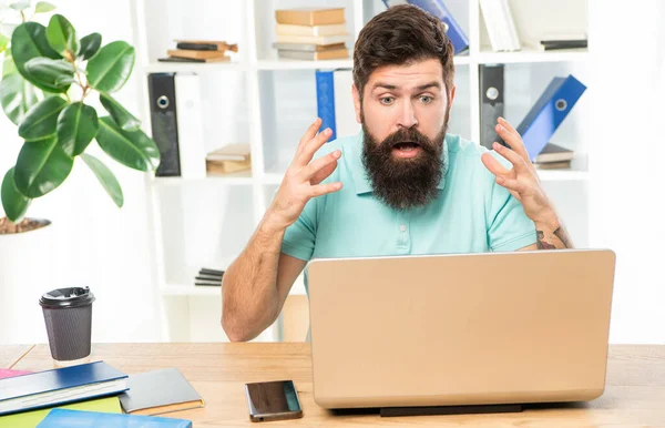 Shocked guy with jaw dropped staring in laptop at office desk, shock — kuvapankkivalokuva