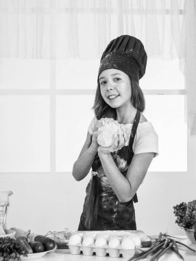 Aşçı çocuk para kazanıyor. Çocuk evde sağlıklı yemekler hazırlar ve aşçı üniforması giyer. Oda servisi ve ev işleri. Çocukluk gelişimi. Küçük kız mutfakta yemek pişiriyor. Mutfak eşyaları.