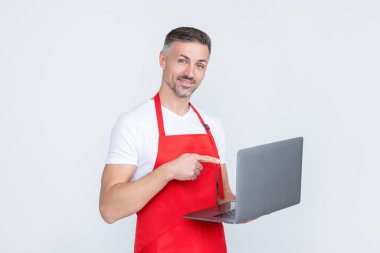 cheerful mature man in apron chatting on computer