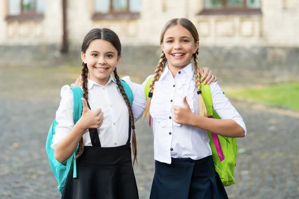 Happy children together in school uniform with backpack. thumb up — Foto de Stock