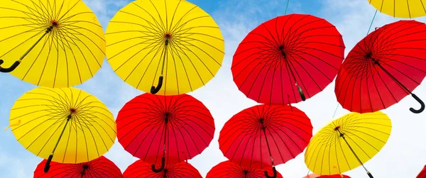 Red and yellow umbrellas hanging sky background bottom-up — Stok fotoğraf