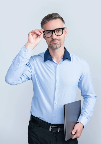 Mature man in eyeglasses holding pc on grey background — стоковое фото