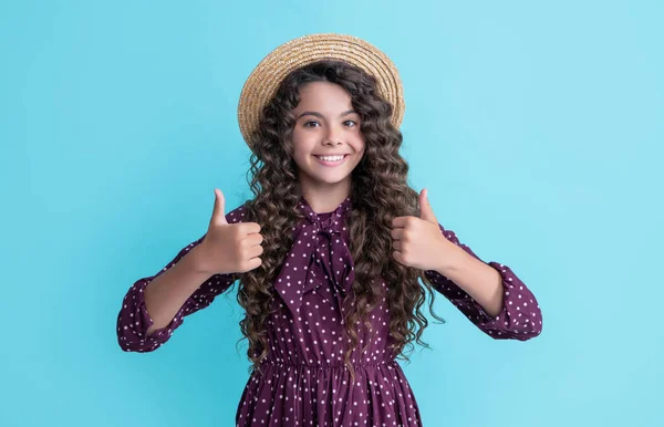 Щаслива дитина в солом'яному капелюсі з довгим брюнеткою кучеряве волосся на синьому фоні — стокове фото