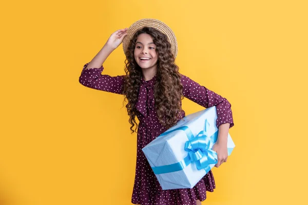 Positive child with curly hair hold present box on yellow background — Stock fotografie