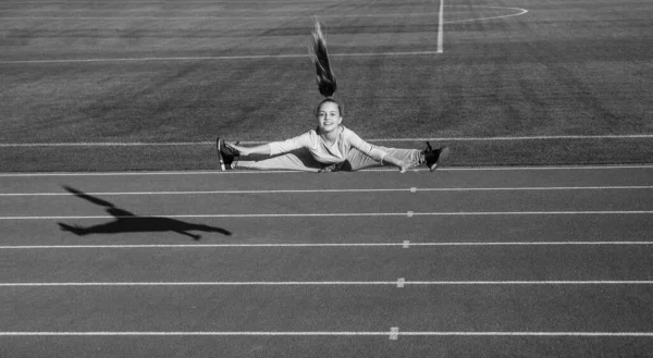 Adolescente chica saltar en split al aire libre en pista de carreras estadio, energía —  Fotos de Stock